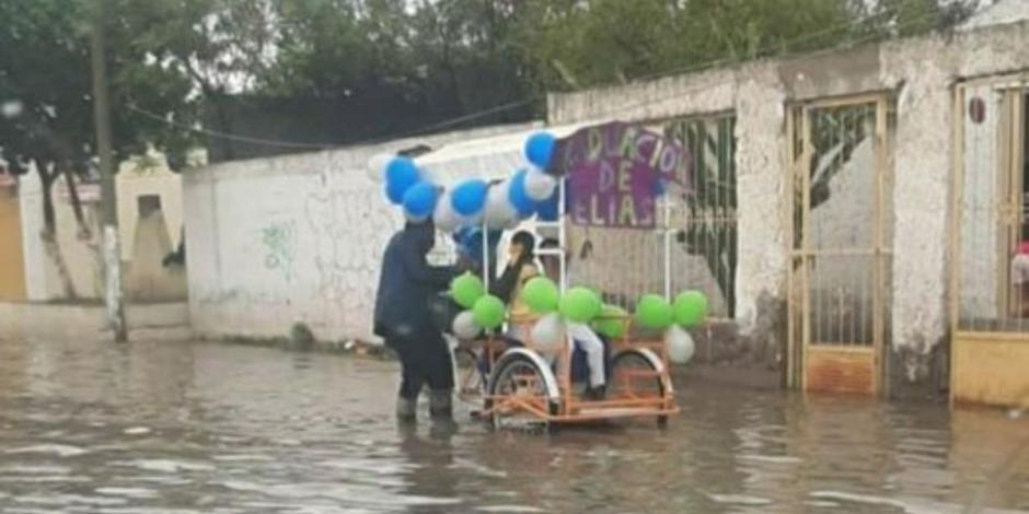 En redes sociales se difundió una fotografía en donde el padre empuja su triciclo con su hijo adentro para celebrar su graduación, a pesar de las inundaciones en la zona.