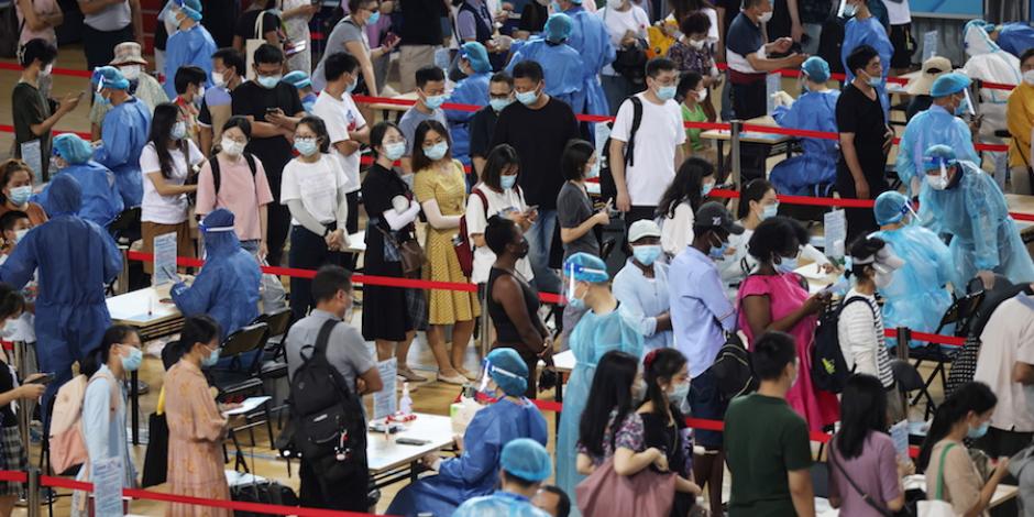 Personas hacen fila en el centro deportivo de Gulou, en China, para realizarse una prueba Covid, ante el aumento de nuevos casos en la ciudad, ayer.