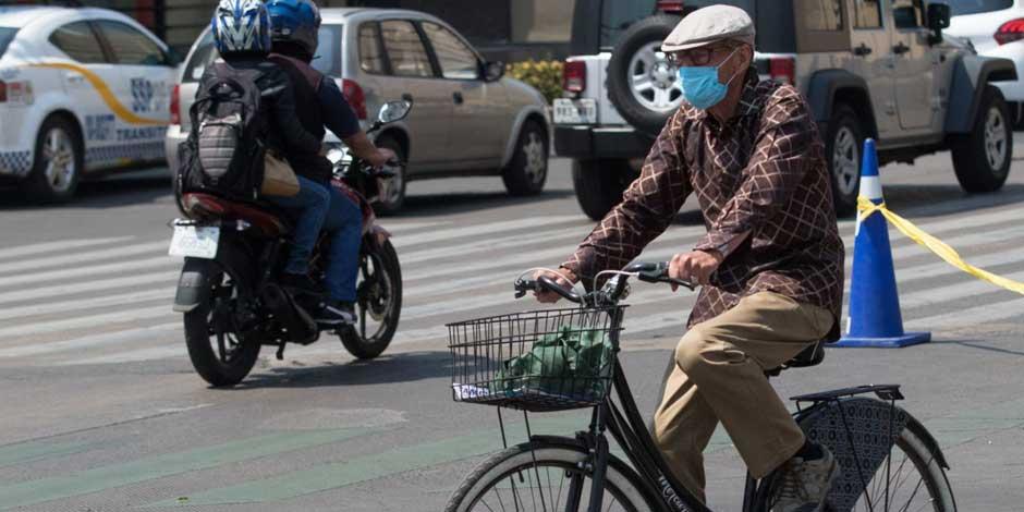Un ciclista con cubrebocas avanza por las calles de la ciudad de México en su bici