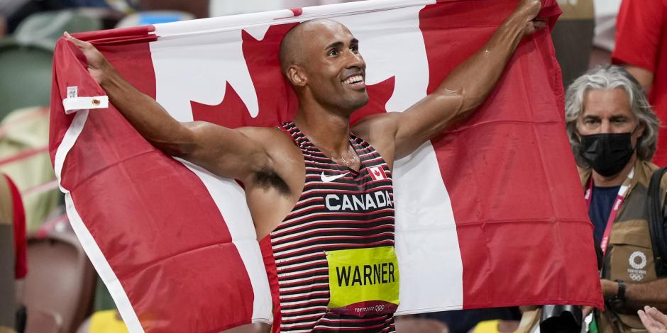 Damian Warner, con la bandera de Canadá, luego de obtener la presea áurea en el decatlón en Tokio 2020.