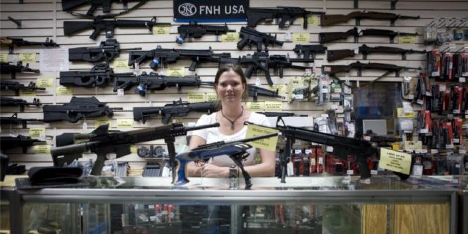 Una vendedora posa detrás del aparador de una tienda de armas en Estados Unidos.