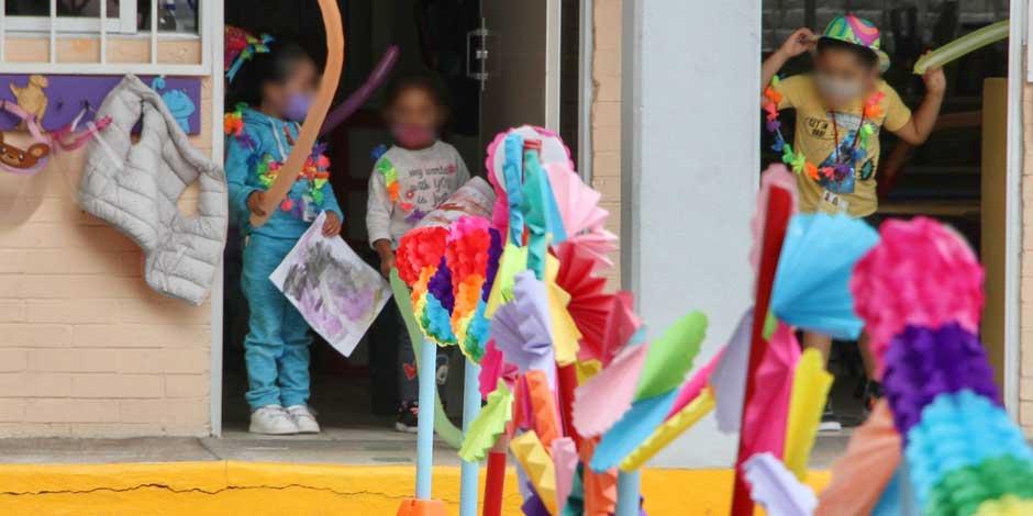 Niños con cubrebocas esperan el llamado de sus profesoras durante la hora de salida en un jardín de niños