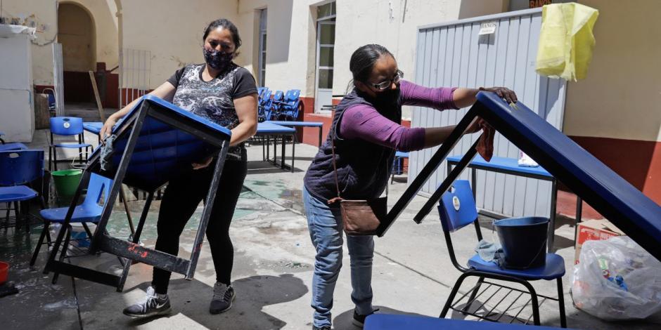 Madres de estudiantes realizan limpieza en escuelas de Puebla, ayer.