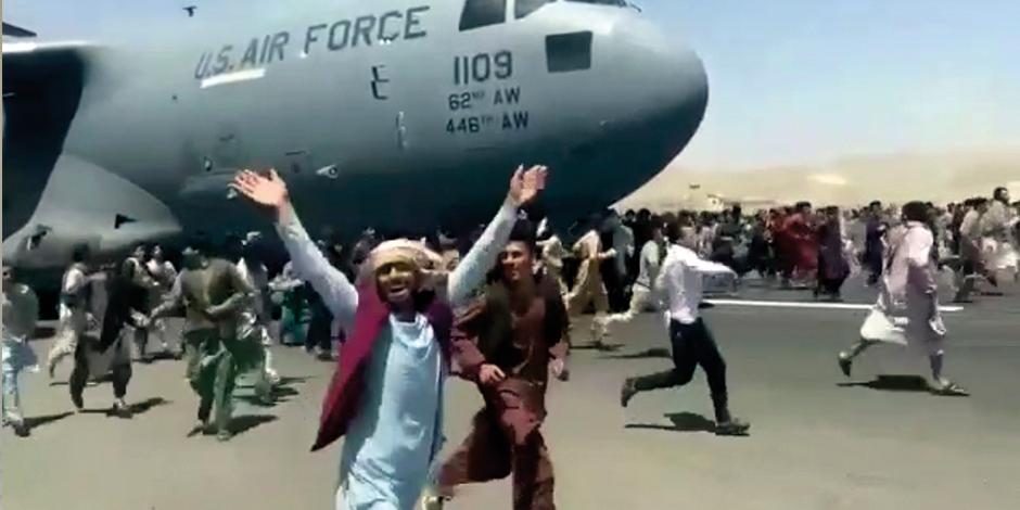 Ciudadanos persiguen un avión de EU para salir de Kabul, ayer.