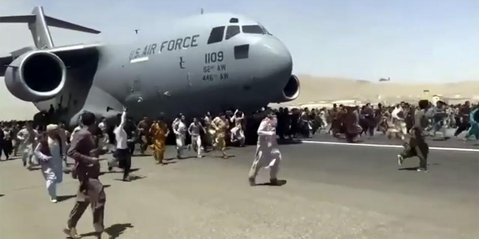 Cientos de personas corren al  rodar de un avión en el aeropuerto de Kabul, ayer.