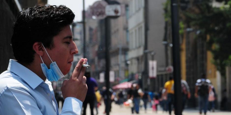 Un hombre fuma un cigarro sobre la calle de Madero.