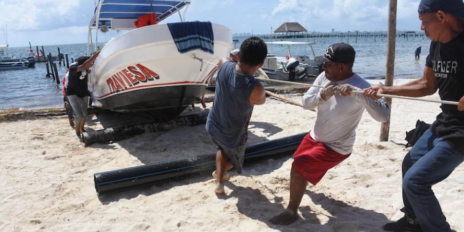 Pescadores retiran sus embarcaciones del mar, horas antes de la llegada de Grace, que este jueves impactó a la Península de Yucatán.