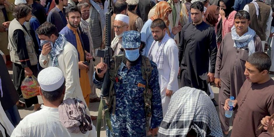 Un miembro de las fuerzas de seguridad talibanes monta guardia entre las multitudes de personas que pasan por una calle en Kabul, Afganistán