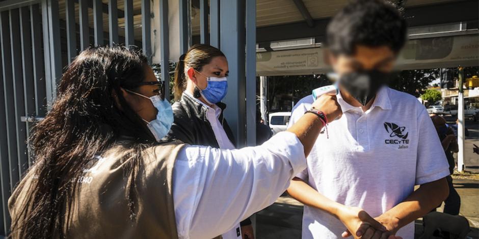 Personal escolar toma la temperatura a un joven en un escuela en Jalisco.