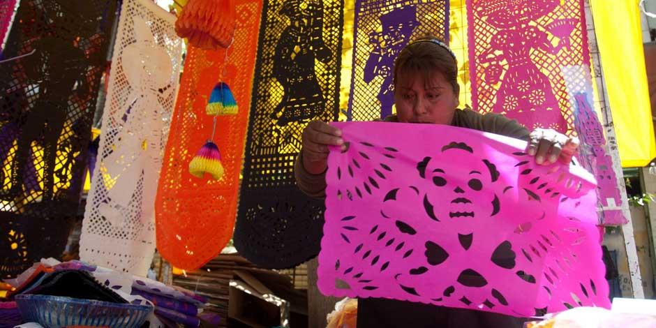Una mujer vende papel picado en el mercado de la Merced para la celebración del Día de Muertos.