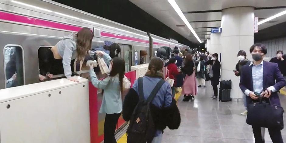 Pasajeros en Kokuryo ayudan a otros a salir por la ventana del tren en el que se encontraba el sospechoso disfrazado, ayer.