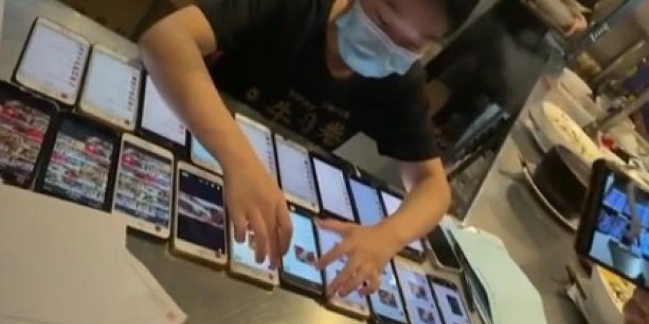 Empleada de restaurante en China trabaja con 20 celulares casi a la vez