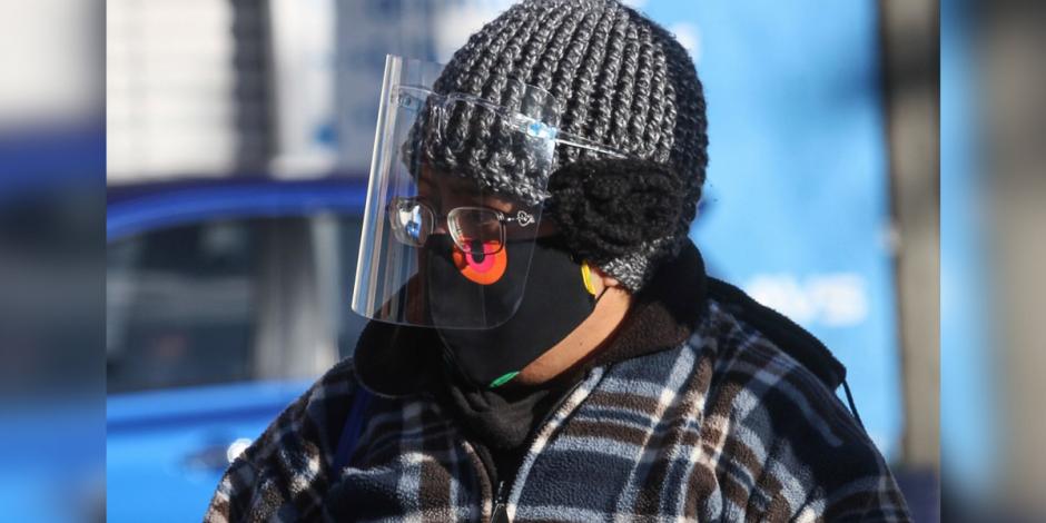 En esta imagen de archivo, una persona se protege del frío con gorro y chamarra; además, utiliza una protección de plástico y cubrebocas para evitar contagiarse de enfermedades respiratorias