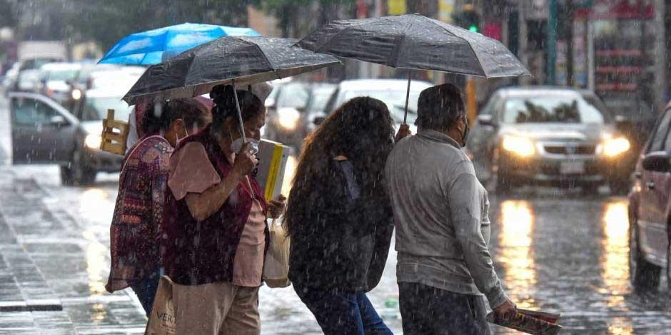 Capitalinos se cubren de las fuertes lluvias en calles de la CDMX.