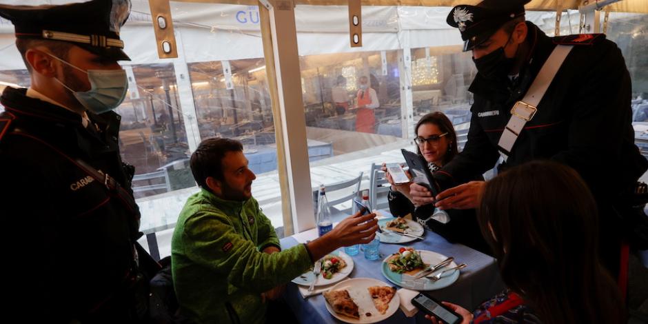En europa algunas naciones como Francia e Italia prohíben entrada en restaurantes, bares y hasta al transporte a personas que no están protegidas; en la imagen, carabineros revisan certificados a comensales, ayer en Nápoles.