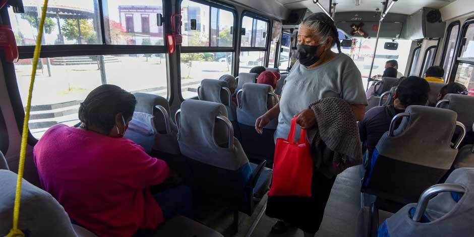 COVID-19: Una mujer en autobús se protege del coronavirus, en su mano lleva una bolsa roja