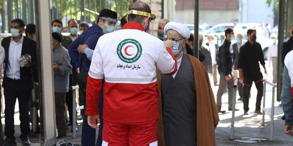 Funcionarios de salud controlan la temperatura corporal de lfieles durante la primera oración del viernes en Teherán, Irán