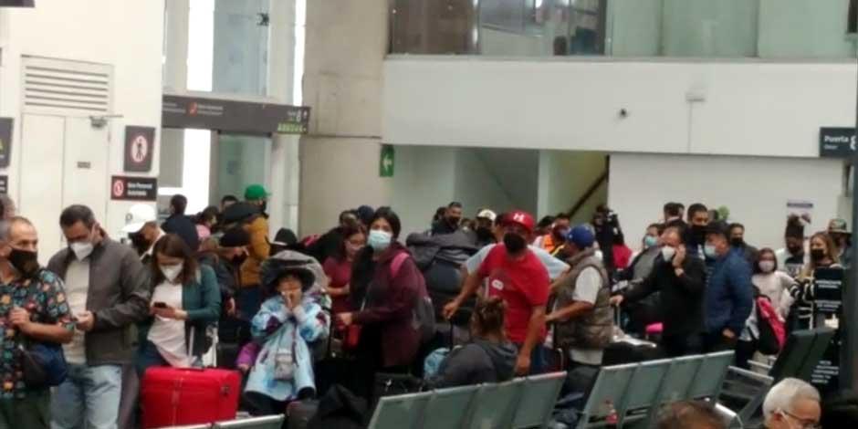 Largas filas de pasajeros con cubrebocas que esperan para documentar su equipaje ante la falta de personal operativo y administrativo en el AICM
