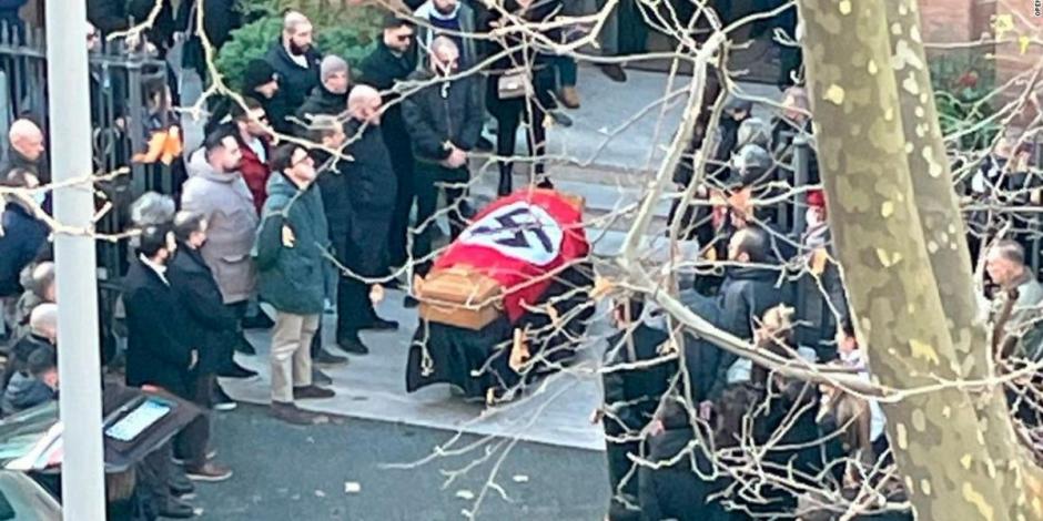 La imagen muestra a personas alrededor de un féretro con la bandera nazi. El funeral fue celebrado en las afueras de la iglesia de Santa Lucía en Roma, Italia, el pasado lunes.