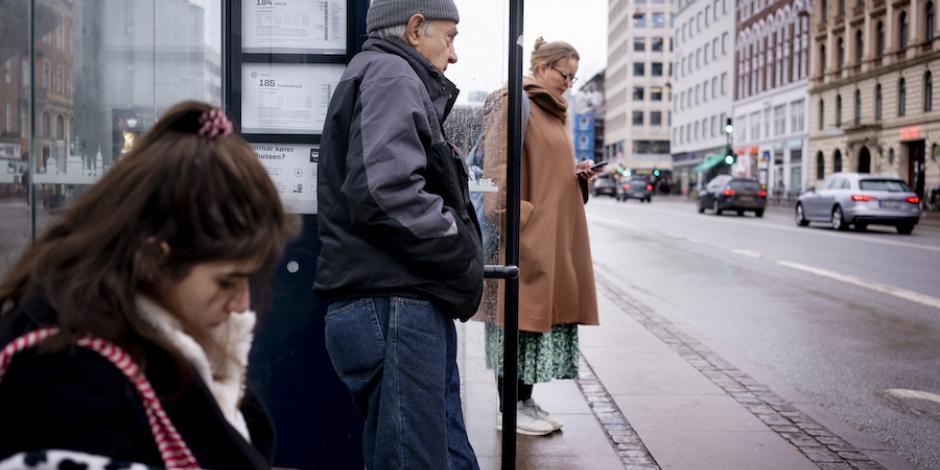 Ciudadanos daneses sin cubrebocas esperan el transporte público tras retiro de restricciones.