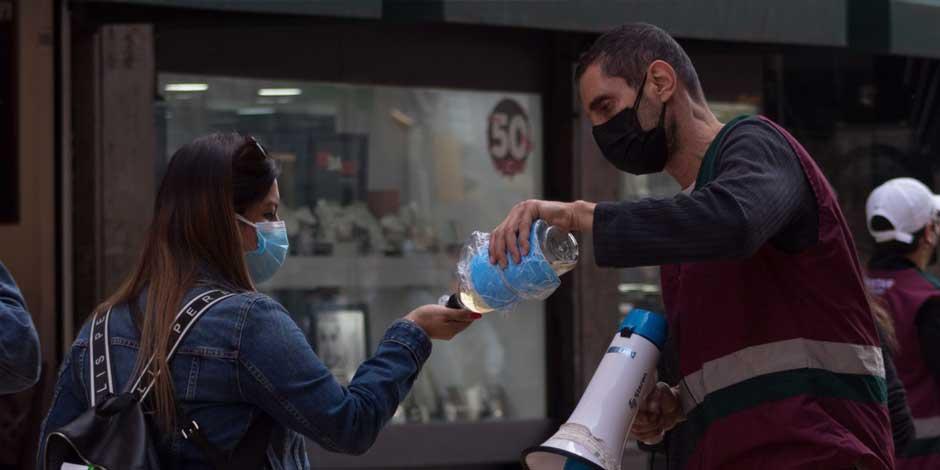 Un trabajador del gobierno capitalino reparte gel antibacterial en las inmediaciones del Centro Histórico