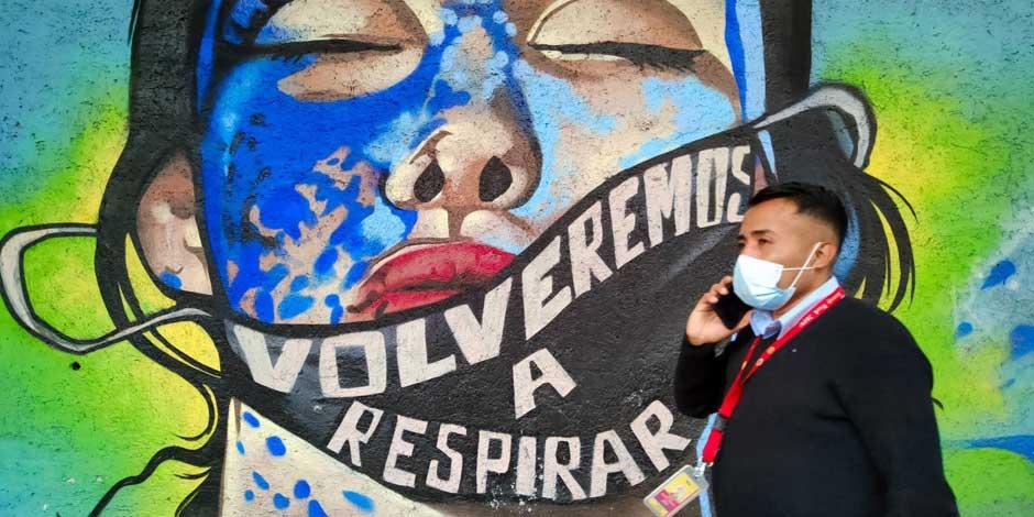 COVID-19: Una persona camina frente a un mural con el mensaje "Volveremos a respirar"