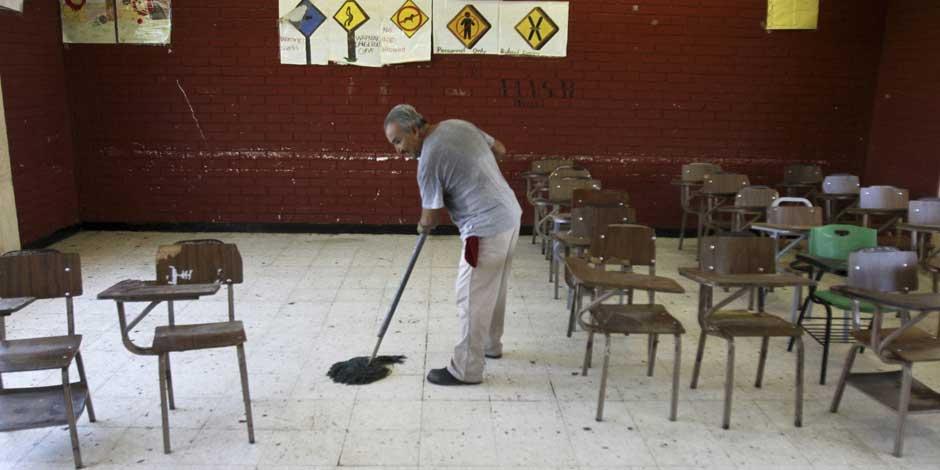 Una persona limpia un salón de clases