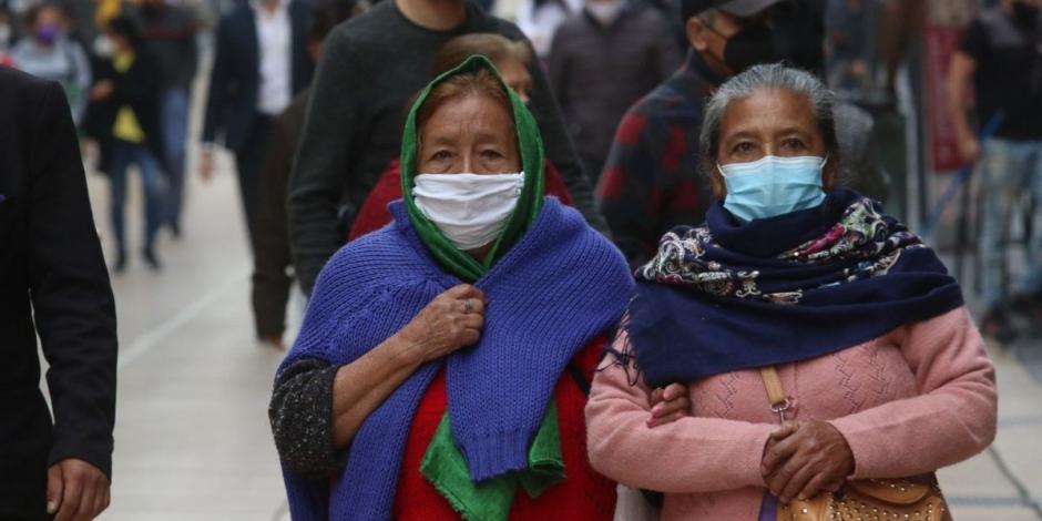 Dos mujeres caminan con ropa abrigadora ante el frío registrado en calles de la CDMX.