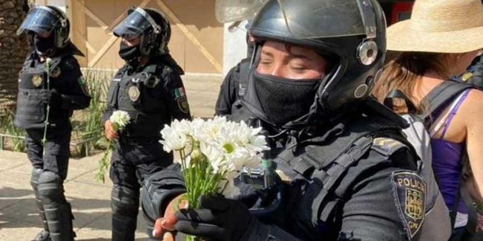 Una mujer entrega flores a una policía de la Secretaría de Seguridad Ciudadana, en el marco de las movilizaciones del 8M.