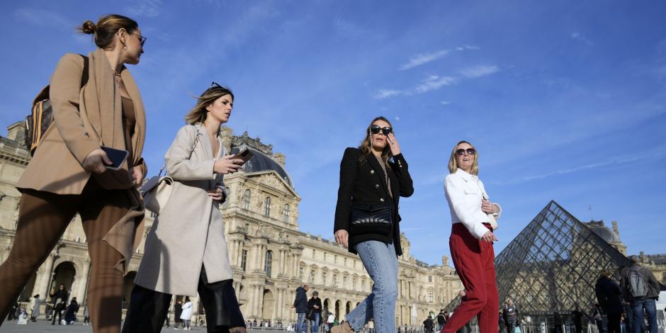 Turistas caminan frente al Museo de Louvre, sin cubrebocas.