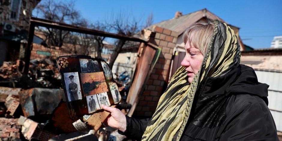 Una mujer inspecciona sus pertenencias en las ruinas de su casa que fue atacada en un ataque militar, en medio de la invasión rusa en Ucrania, en Kiev.