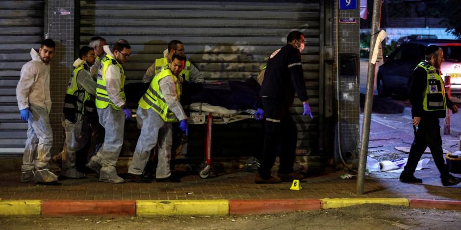 Personal médico y rescatistas israelíes evacuan un cadáver de la escena de un ataque en el que hombres armados mataron a personas en una calle principal de Hadera, Israel.