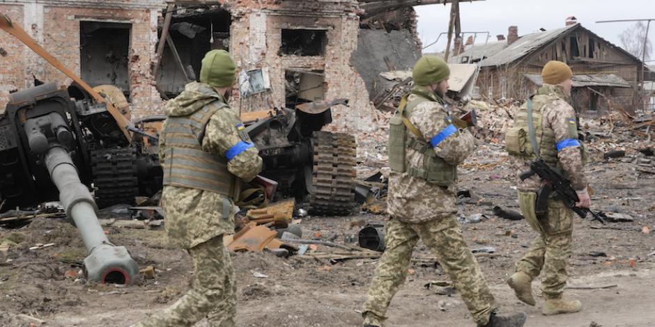 Tropas ucranianas recorren zonas afectadas en Kiev, frente a inmuebles severamente dañados.