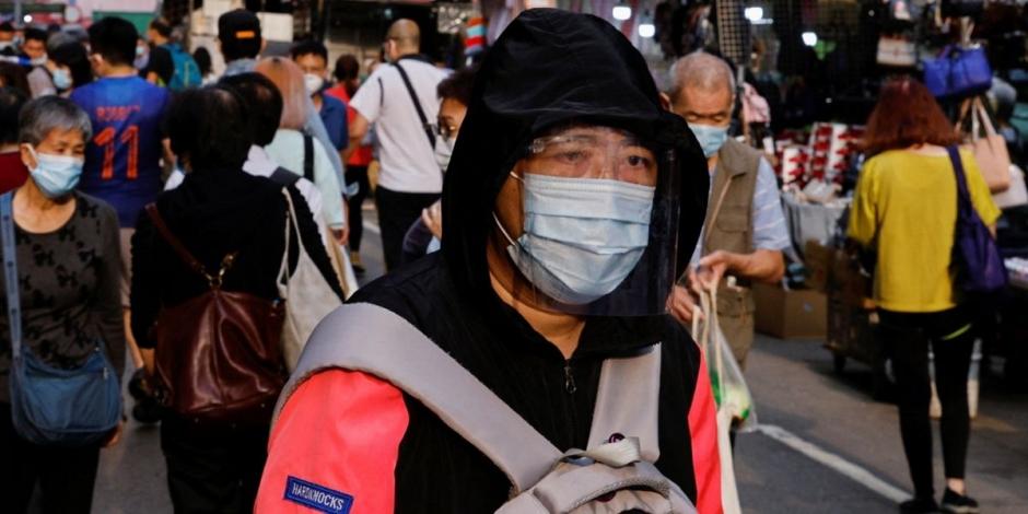 Un hombre con cubrebocas y máscara facial camina en el mercado húmedo en Hong Kong, China, mientras la ciudad atraviesa su brote más letal de COVID-19.