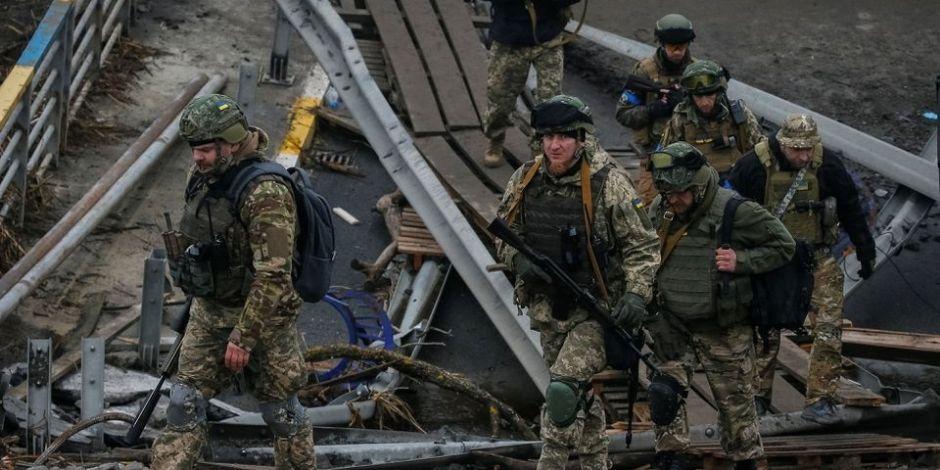 Militares de Ucrania caminan sobre un puente destruido mientras continúa la invasión rusa.
