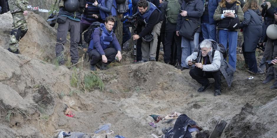Periodistas observan cuerpos semienterrados en zonas liberadas.