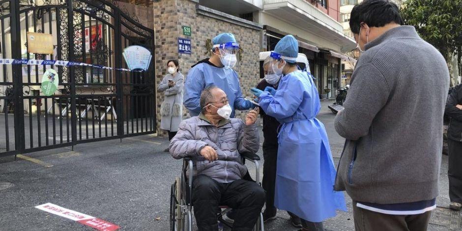 En China, expertos de salud ayudaron a un hombre en silla de ruedas durante las pruebas masivas COVID-19.