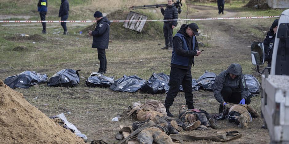 Médicos forenses rastrean cuerpos al interior de fosas en zonas cercanas a Kiev, ayer.
