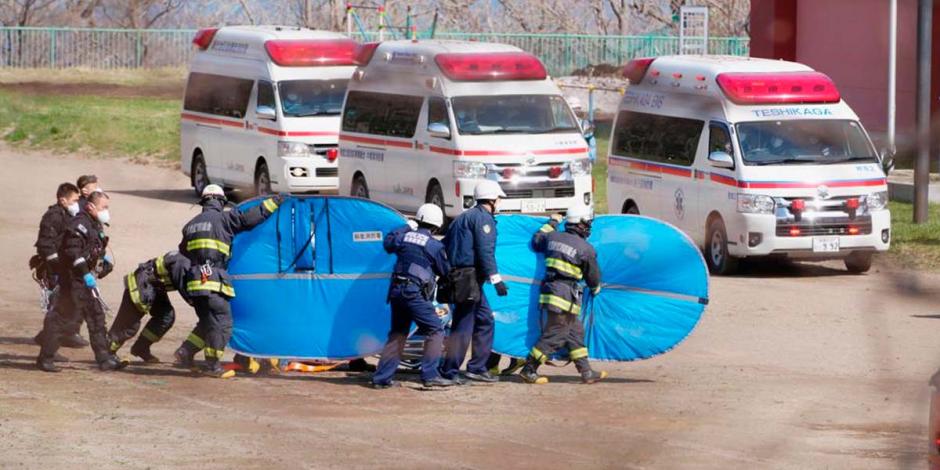 Bomberos cubren con escudos a una persona a la que trasladan a un hospital después de ser rescatada en el mar en Shari, en la isla norteña de Hokkaido, el domingo 24 de abril de 2022