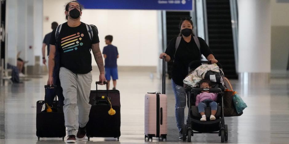 Viajeros arriban con mascarillas a un aeropuerto de Estados Unidos.