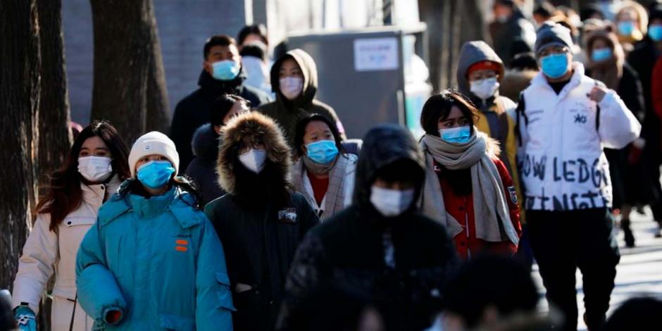 Gente caminando por las calles de China mientras usa cubrebocas por la pandemia de COVID-19