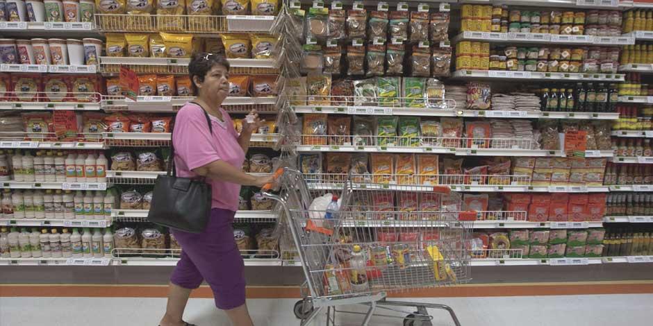 En la imagen, una mujer con su carro de compras en un supermercado
