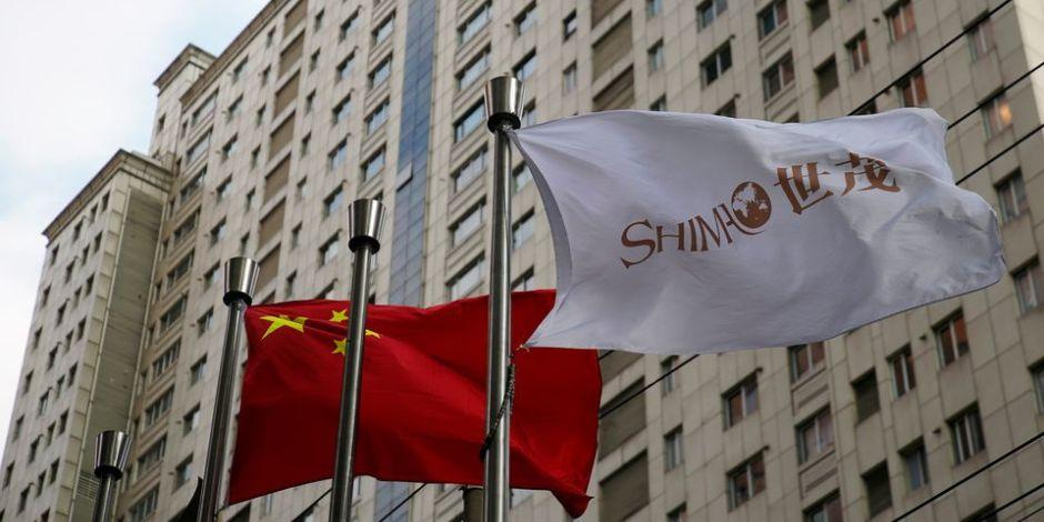La bandera del promotor inmobiliario Shimao Group ondea junto a una bandera china en Shanghai, China.