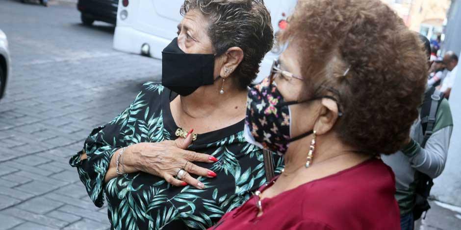 Un par de mujeres utilizan cubrebocas para protegerse del COVID-19 mientras se encuentran en la calle|