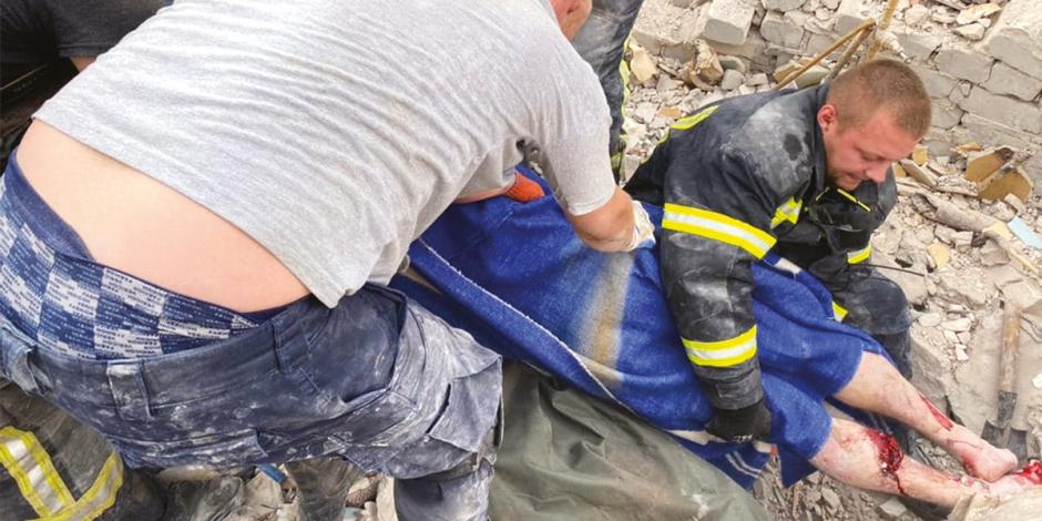 Rescatistas ayudan a sacar a víctimas y buscan  a sobrevivientes en edificio residencial bombardeado, ayer.