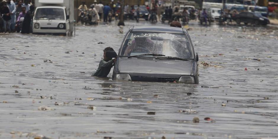 En la calle inundada en Karachi, Pakistán un menor y un auto se desplazan en el agua.