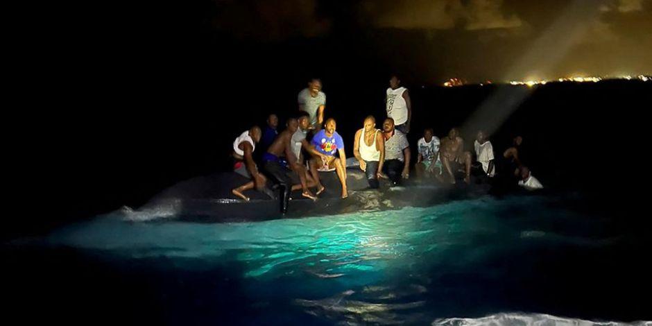 Sobrevivientes del naufragio sobre un bote volcado mientras aguardan a ser rescatados.