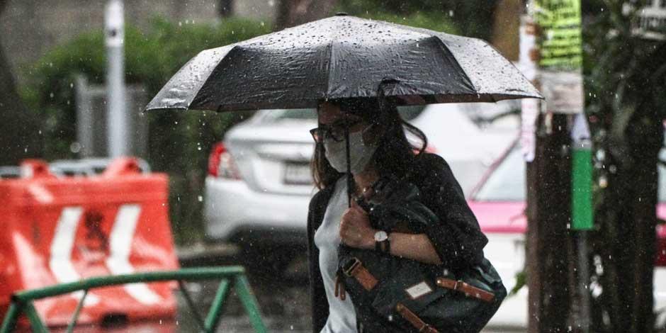 Una mujer camina protegiéndose de la lluvia con un paraguas