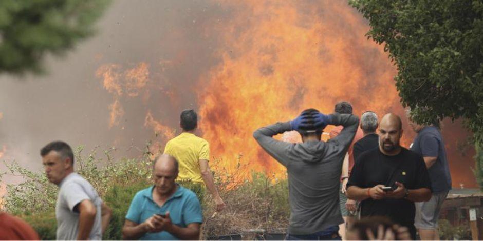 Ciudadanos se alejan de un incendio forestal en Añón de Moncayo, en Zaragoza, España.