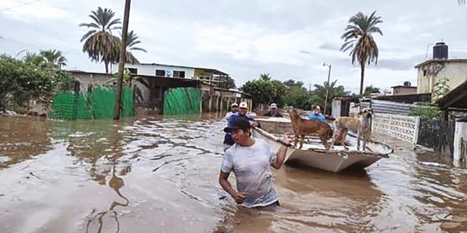 Un hombre conduce en lancha a sus perros por una calle inundada de Empalme, ayer.